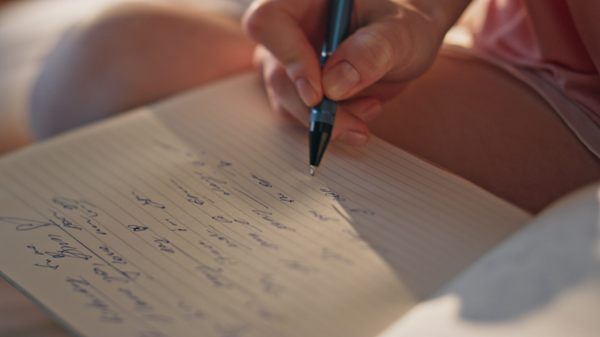 Closeup hand writing diary in golden sunlight. Unknown romantic girl make notes in morning pajamas. Inspired teenager writer noting poems enjoying weekend at home. Personal notebook planning concept.